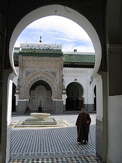 Courtyard of a mosque with a tiled fountain and ornate entrance framed by a large arch