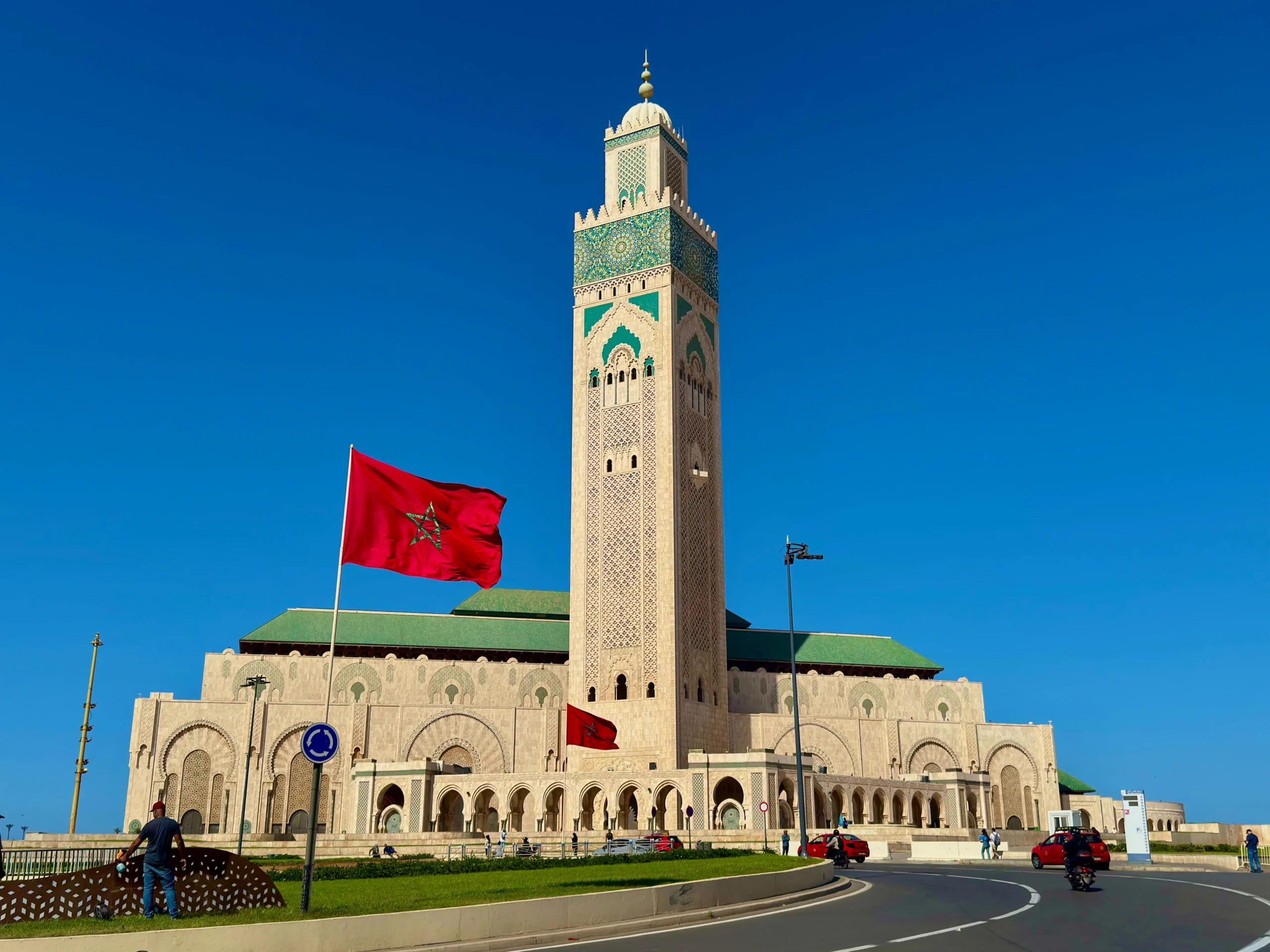 Hassan II Mosque with Moroccan flag under blue sky